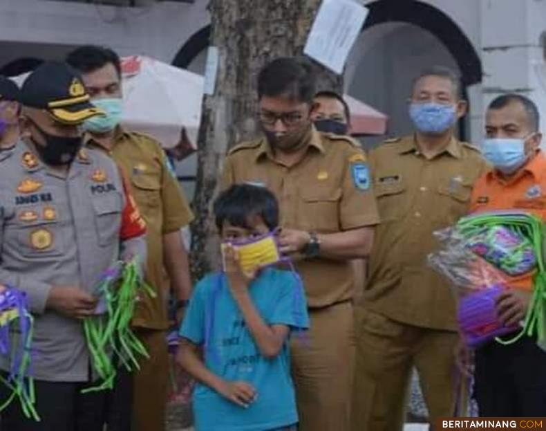 Wako Deri Asta saat memasangkan masker kepada seorang bocah disaksikan Kapolres Sawahlunto AKBP Junaidi Nur dan pejabat Kepala Dinas Pemko. Foto: Iyos